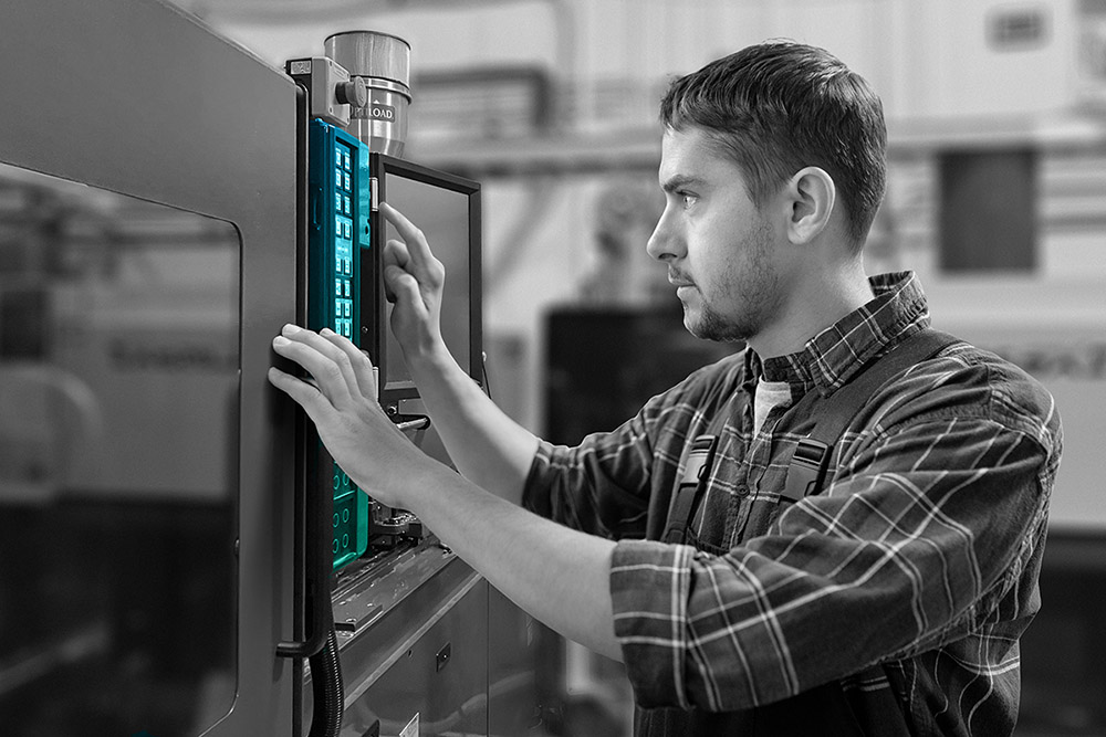 Worker operating injection molding machine control panel